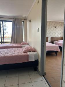 a room with two beds and a window at Hotel Capri in Iquique