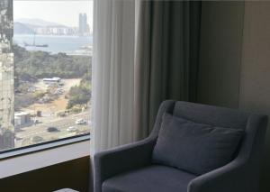 a chair in front of a window with a view at Baymond Hotel in Busan