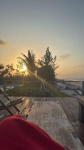 a sunset over the beach with benches on a deck at Chalé da Ana in Tutóia
