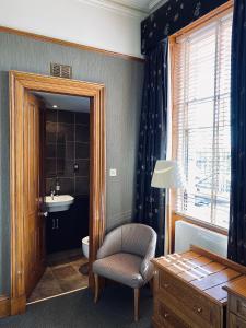 a bathroom with a toilet and a chair and a sink at The Dutch Mill Hotel in Aberdeen