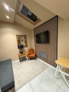 a living room with a chair and a flat screen tv at 1885 The Retreat in Matlock