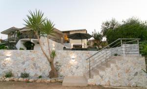 a house with a stone wall and stairs with an umbrella at Akrolithia Guest House in Valanidorachi +10 photos
