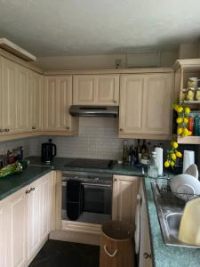 a kitchen with white cabinets and a stove top oven at Pine Tree Cottage in Linslade