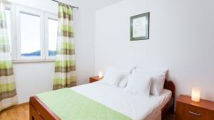 a bedroom with a white bed with two windows at Villa Julija by Villas Guide in Smokvica +28 photos