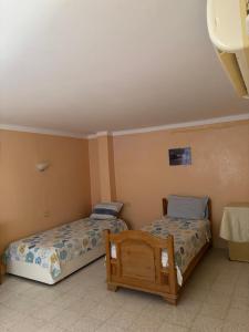 a bedroom with two beds and a table in it at Cosy Apparemment in Nabeul