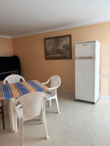 a kitchen with a table and a white refrigerator at Cosy Apparemment in Nabeul