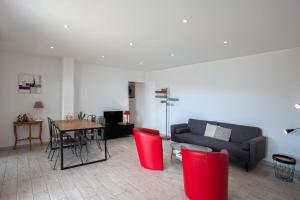 a living room with a couch and a table with red chairs at Casa Bianca in LʼÎle-Rousse