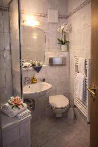 a white bathroom with a sink and a toilet at Burghof Hotel in Schwarzatal
