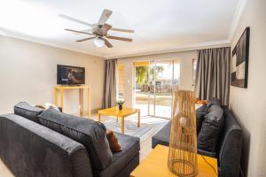 a living room with two couches and a ceiling fan at Carousel Eco Estate in Temba
