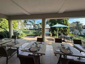 a dining room with tables and chairs and a patio at Highgrove Guesthouse Morningside Sandton in Sandton