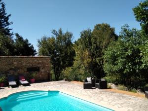 a swimming pool in a yard with chairs and trees at Les feuillets de la Buire in Monteux