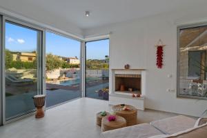 a living room with a fireplace and a view of a pool at Annassa Experience Villa 2' walk from Almyrida beach in Almyrida