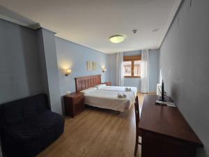 a bedroom with a bed and a couch and a table at HOTEL EL ROBLE PALENTINO in Cervera de Pisuerga