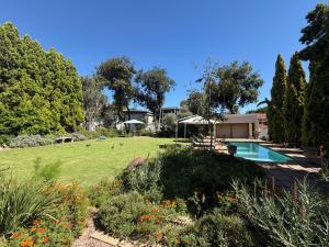 a garden with a swimming pool and a yard with flowers at Highgrove Guesthouse Morningside Sandton in Sandton