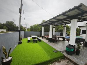 a patio with green grass and a pergola at Anna Homestay Penarik Private Pool in Kampong Ru Sepuloh