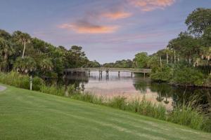a bridge over a river with a green yard at OG14: 14 Ocean Green in Kiawah Island
