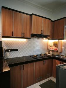 a kitchen with wooden cabinets and black counter tops at Anna Homestay Penarik Private Pool in Kampong Ru Sepuloh