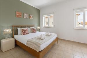 a bedroom with a large bed and two windows at Casa da Shaka Baleal in Ferrel