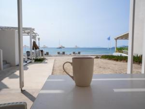 a coffee cup sitting on a table next to the beach at Votsalo in Kardamaina