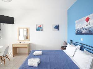 a blue and white bedroom with a bed and a desk at Votsalo in Kardamaina