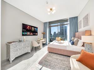 a bedroom with a king sized bed and a tv at Peninsula One Suites by Prestige Nest in Dubai