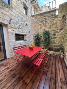 a red table and chairs on a wooden deck at Chez Marie & Nico in Aigues-Mortes
