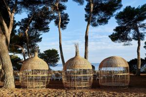 three bird cages on the beach with trees in the background at Iberostar Selection Santa Eulalia Adults-Only Ibiza in Santa Eularia des Riu