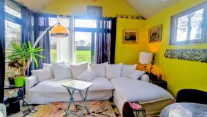 a living room with a white couch and yellow walls at La Demeure du Figuier in Évran