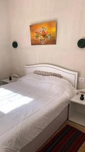 a bedroom with a white bed with a vase of flowers at Maison Bohème Suite Fatima in Midoun