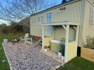 a small shed with a bath tub in the yard at Happy Place Shepherds Hut in Bishops Tachbrook