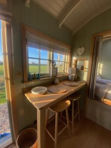 a room with a table and a bed and a window at Happy Place Shepherds Hut in Bishops Tachbrook