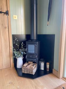 a stove in a room with a plant and a basket at Happy Place Shepherds Hut in Bishops Tachbrook