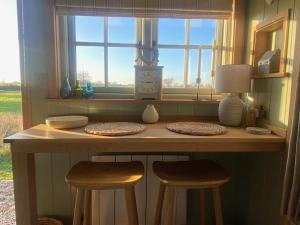 a counter with two stools in front of a window at Happy Place Shepherds Hut in Bishops Tachbrook