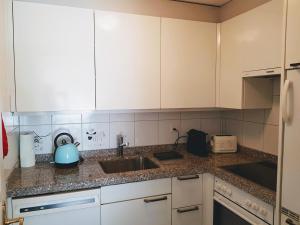 a kitchen with white cabinets and a sink at Davos - Cozy Escape - Mountain Rentals in Davos