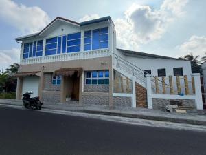 a house with a scooter parked in front of it at Newsy Inn in Hithadhoo