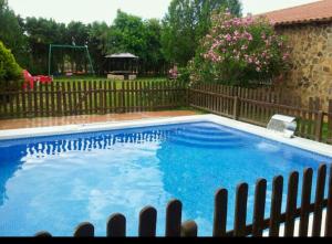 a large blue swimming pool with a wooden fence at Los Jabones in Ciudad Real