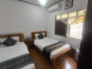 two beds in a small room with a window at Chalern Guesthouse in Luang Prabang
