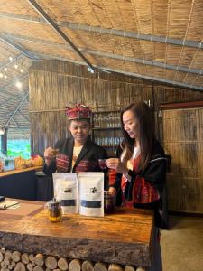 a woman standing at a counter with a girl behind a table at ไร่ชาอาโซ -ที่พักดอยช้าง in Ban Huai Khai