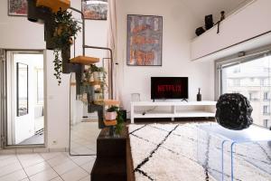 a living room with a tv and a couch at Loft Duplex Terrasse View on Paris in Paris