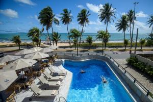 a pool with chairs and umbrellas and the beach at Hardman Praia Hotel in João Pessoa