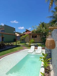 a swimming pool with lounge chairs and a house at Arraia Suítes Pousada in Pipa