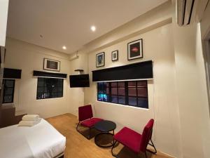 a bedroom with a bed and two red chairs at Star Mews Hotel Changkat Bukit Bintang in Kuala Lumpur