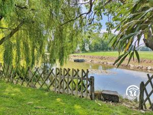 a fence next to a river with a boat in it at La grande reignière in Brécé