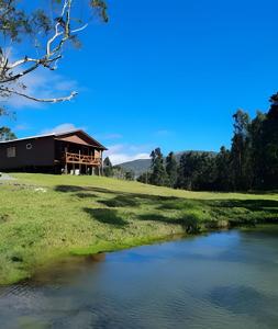 a barn next to a river in a field at Pousada Recanto da Paz in Urupema
