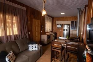 a living room with a couch and a kitchen at Pousada Recanto da Paz in Urupema