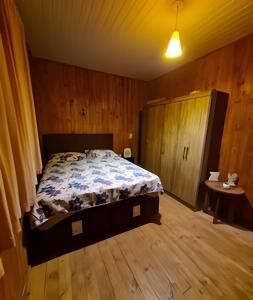 a bedroom with a bed in a wooden room at Pousada Recanto da Paz in Urupema