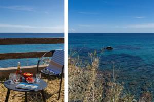 a table with a bottle of wine next to the ocean at Villa Erbalunga in Erbalunga