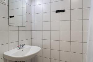 a white tiled bathroom with a sink and a mirror at Faxe Ladeplads Motel in Hylleholt +27 photos