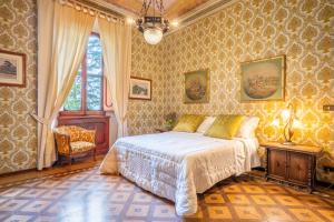 a bedroom with a bed and a chair and a window at Palazzo Tombesi Trecci in Montepulciano