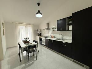 a kitchen with a table and chairs and a kitchen with black cabinets at Terra D'Amuri in Barrafranca